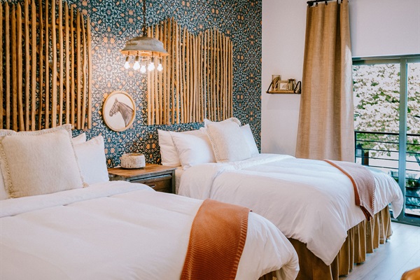 Two queen beds with pillow-top mattresses and premium Comphy linens at the Corral Suite &mdash; a modern Western suite at Gaines Ranch on the Square that sleeps four.
