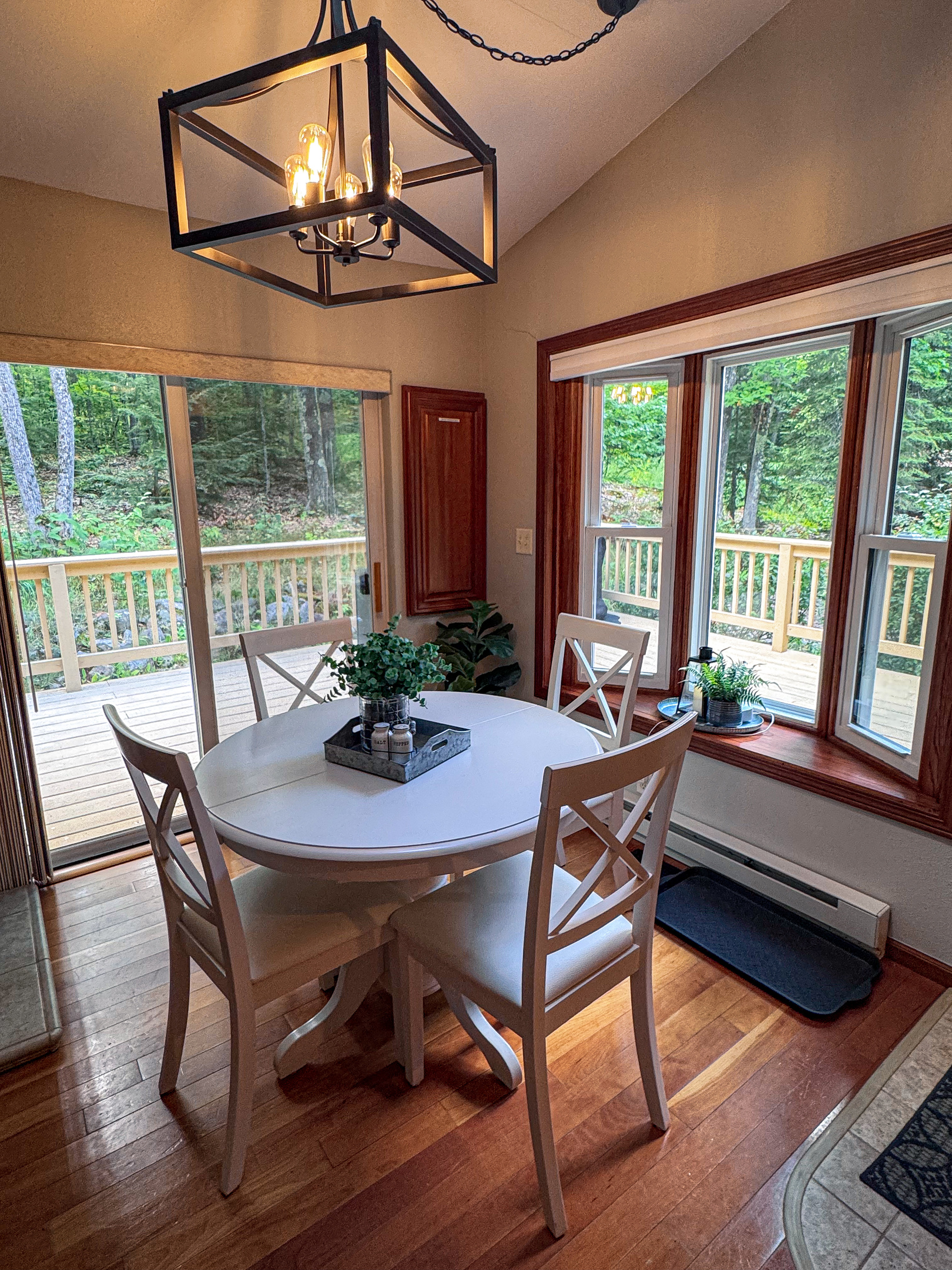 Dining table next to propane fireplace with walk out slider doors and large windows brings in light and wooded views
