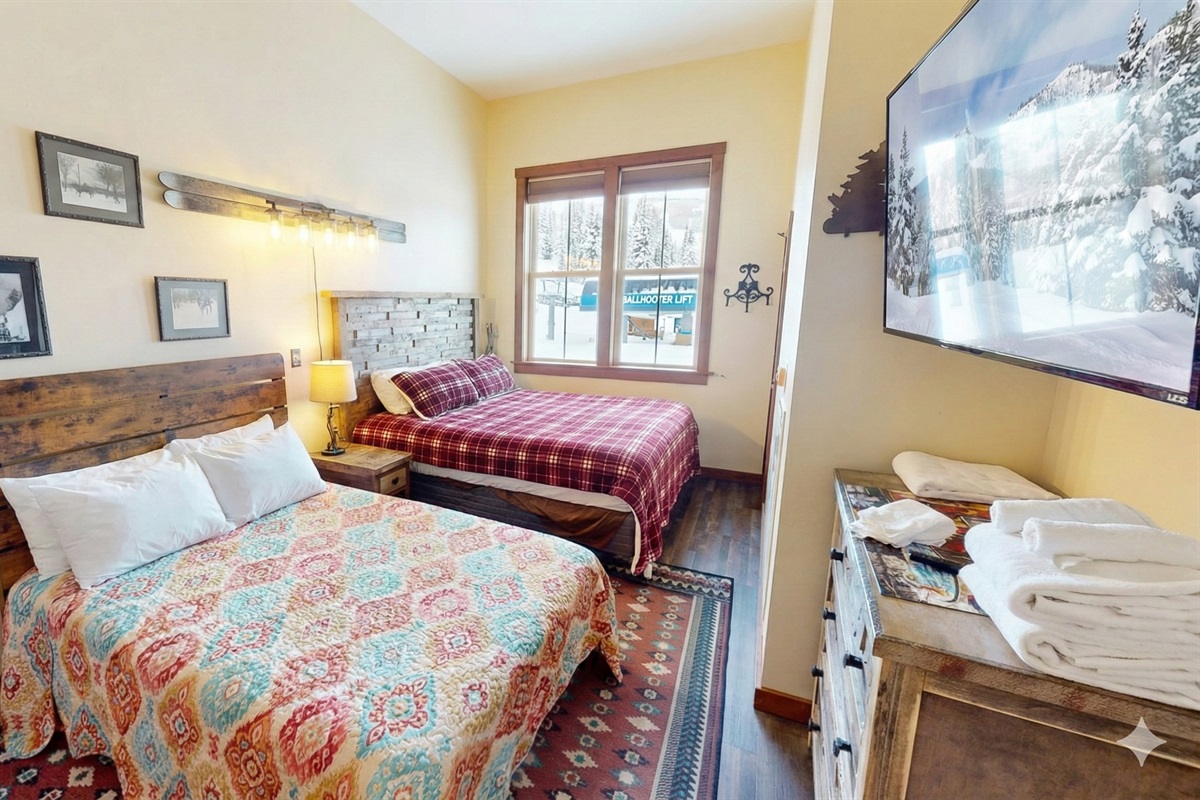 Warm, rustic bedroom with King and full beds and mountain views — comfort meets adventure.