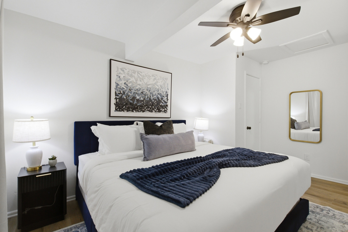 King Bed in Bedroom 1 with bright natural light, Ceiling Fan, and bedside lighting. Restful sleep setup after game day at AT&T Stadium or a day at Six Flags.
