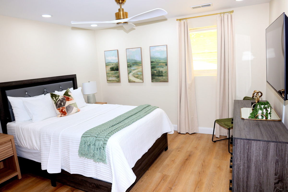 Bright guest bedroom in basement with TV, soft linens, and calming décor