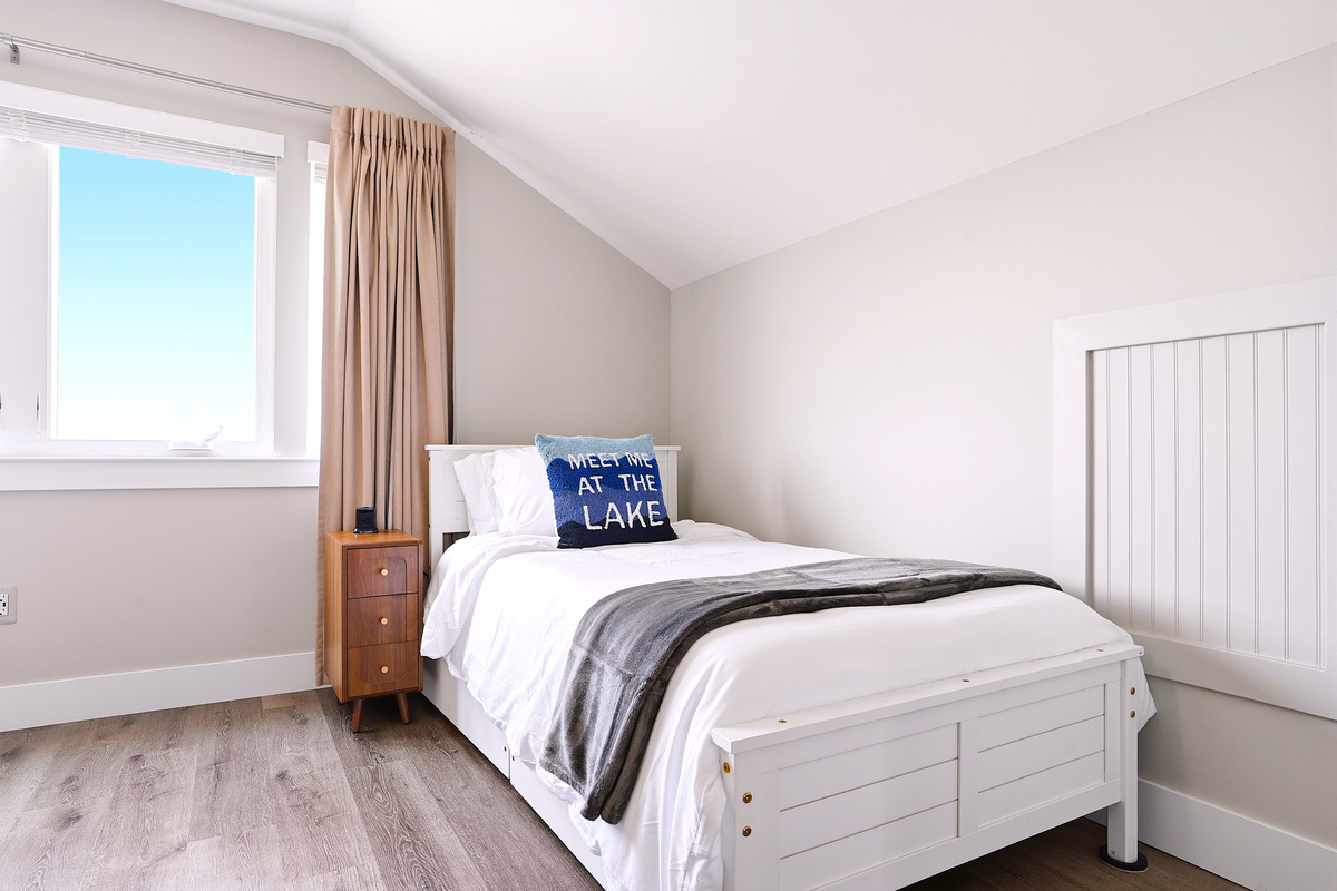 One side of the room offers a cozy queen bed tucked beneath the vaulted ceilings, creating a quiet corner to unwind after a day of adventure.