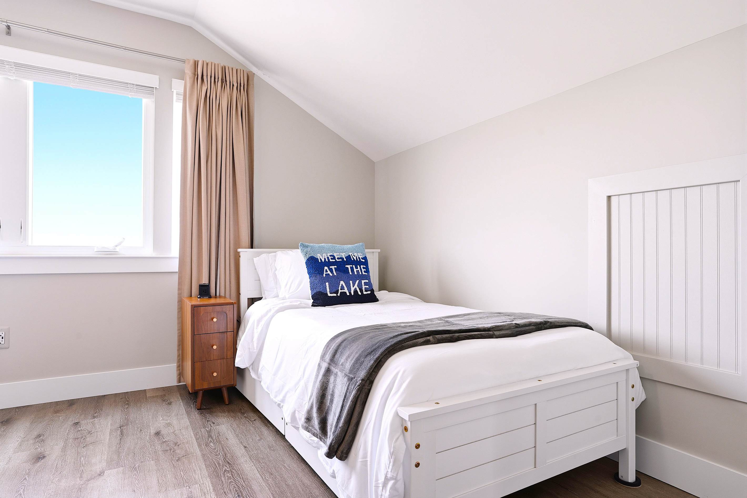 One side of the room offers a cozy queen bed tucked beneath the vaulted ceilings, creating a quiet corner to unwind after a day of adventure.
