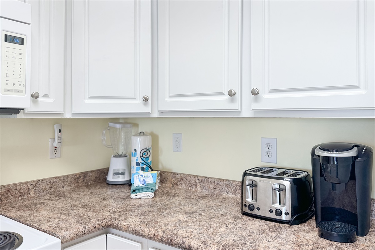 A tidy and functional kitchen countertop. This organized space, complete with coffee makers, a toaster, and a paper towel holder, makes everyday tasks a breeze.