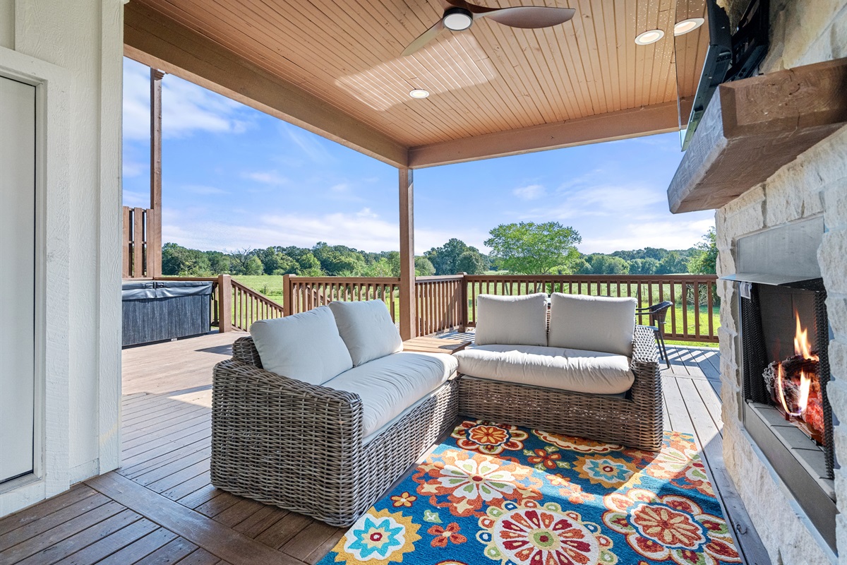 Covered outdoor lounge with fireplace and comfortable seating.