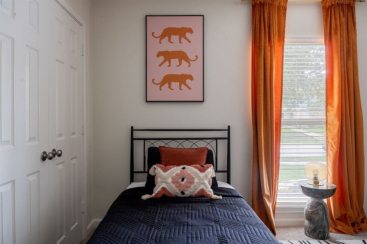 Embrace the charm of this cozy room featuring unique wall art and a comfortable single bed. Natural light streams in through the large window.