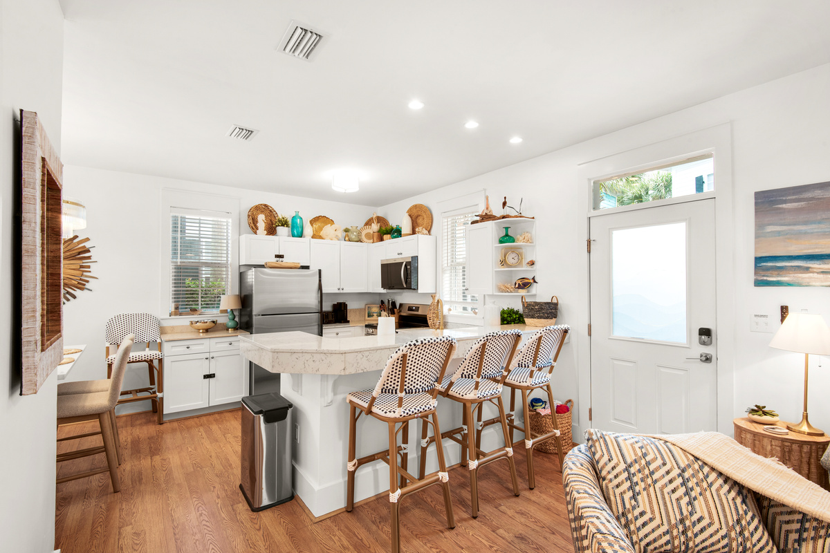 Kitchen island with seating for three at Seagrove Bungalow 103, open to the living and dining areas.