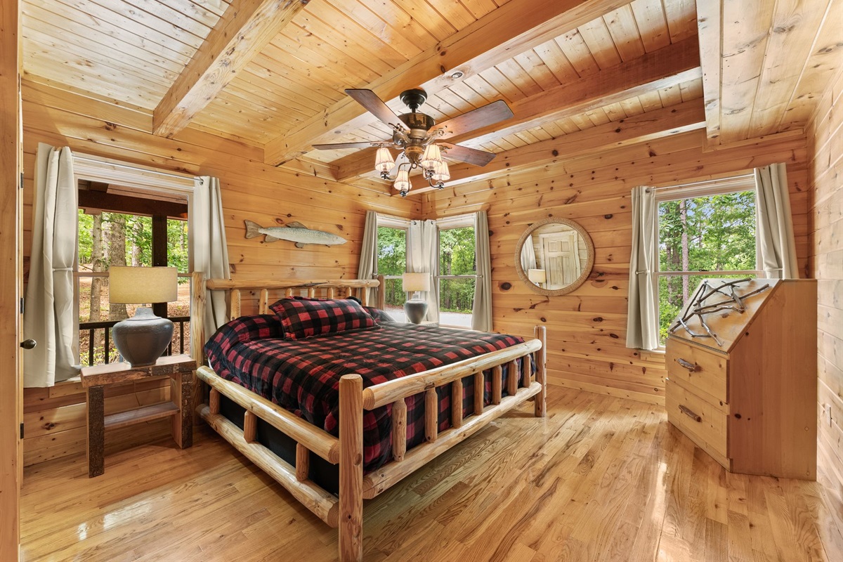 Cozy king-sized bed in the master bedroom with warm wood interiors and peaceful cabin charm.