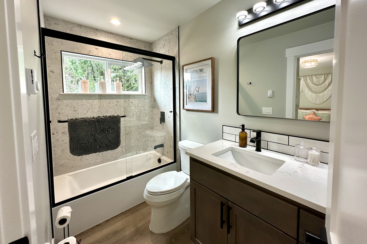 A second upstairs bath with quartz counters, matte black fixtures and a shower–tub combo that works for kids and adults alike.