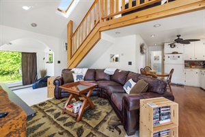 second living room with leather couch and stairs in the background