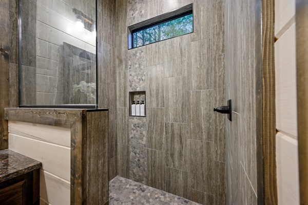 Modern spa vibes with floor-to-ceiling tile and a sleek rainfall head.