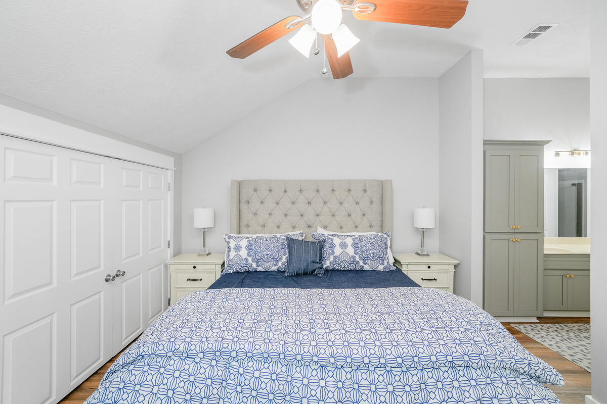 Relax in our spacious primary suite featuring a king-size bed, closet, dresser, en-suite bathroom, premium linens, night lamp, and ceiling fan,