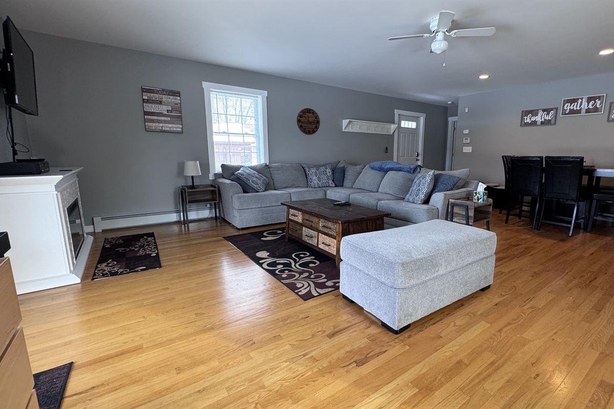 Living room with sizeable L-shaped couch with open concept to kitchen and dining area