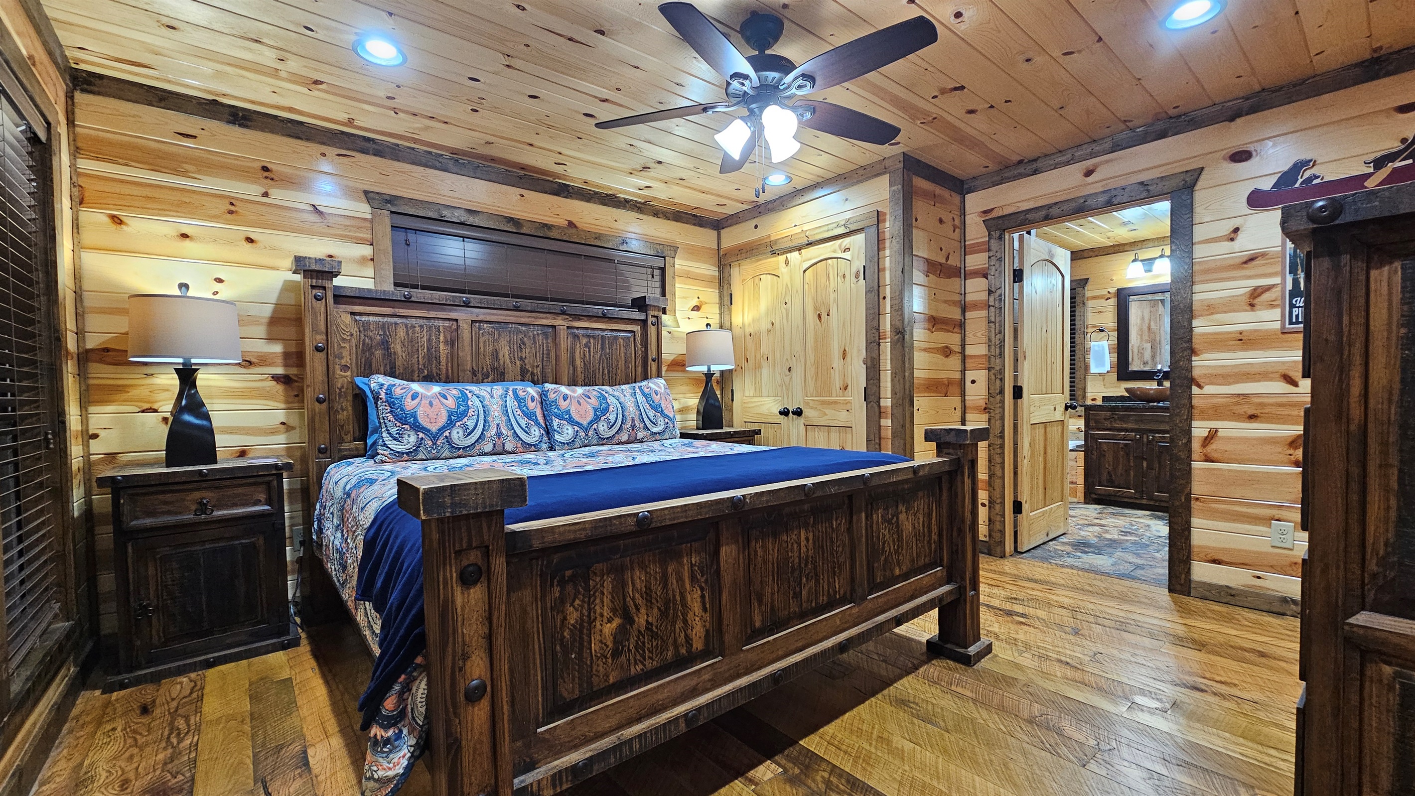 Bedroom 1: Relax in rustic charm with a plush bed and nature views through sunny windows!