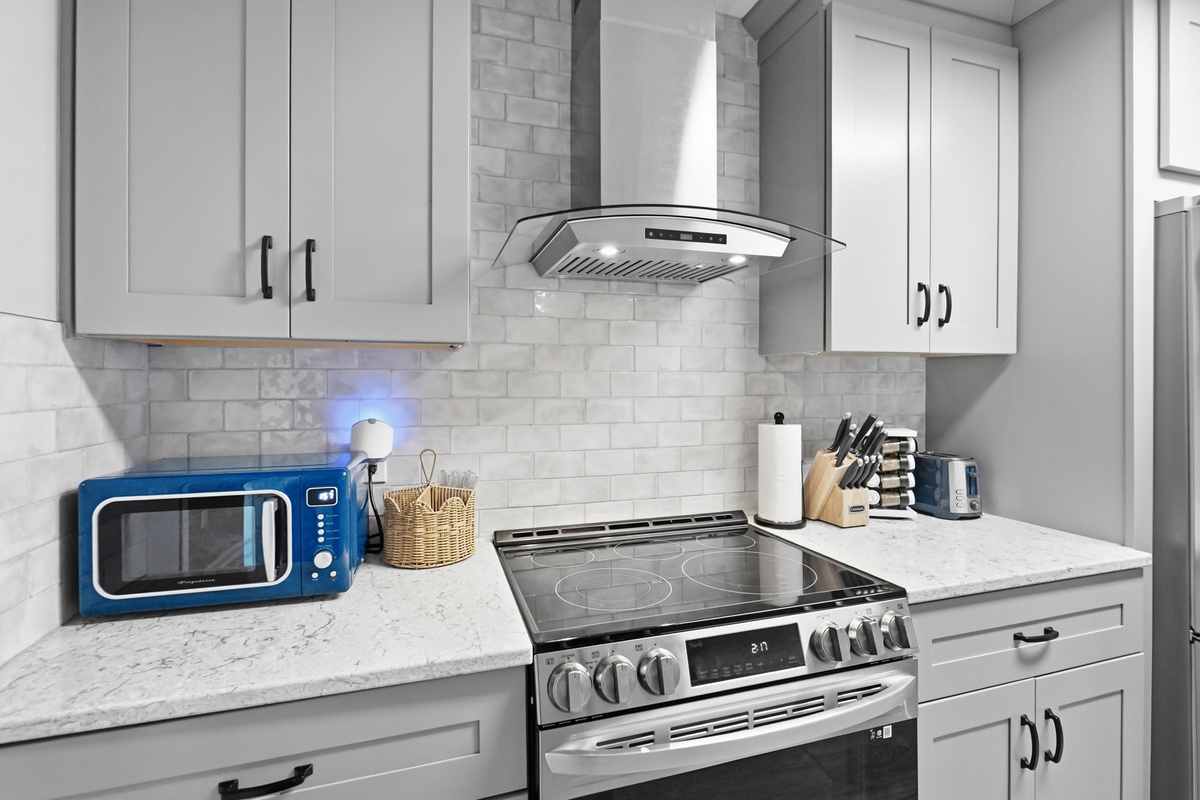The modern kitchen includes a full-size range, microwave, toaster, cookware, and plenty of space for preparing meals.