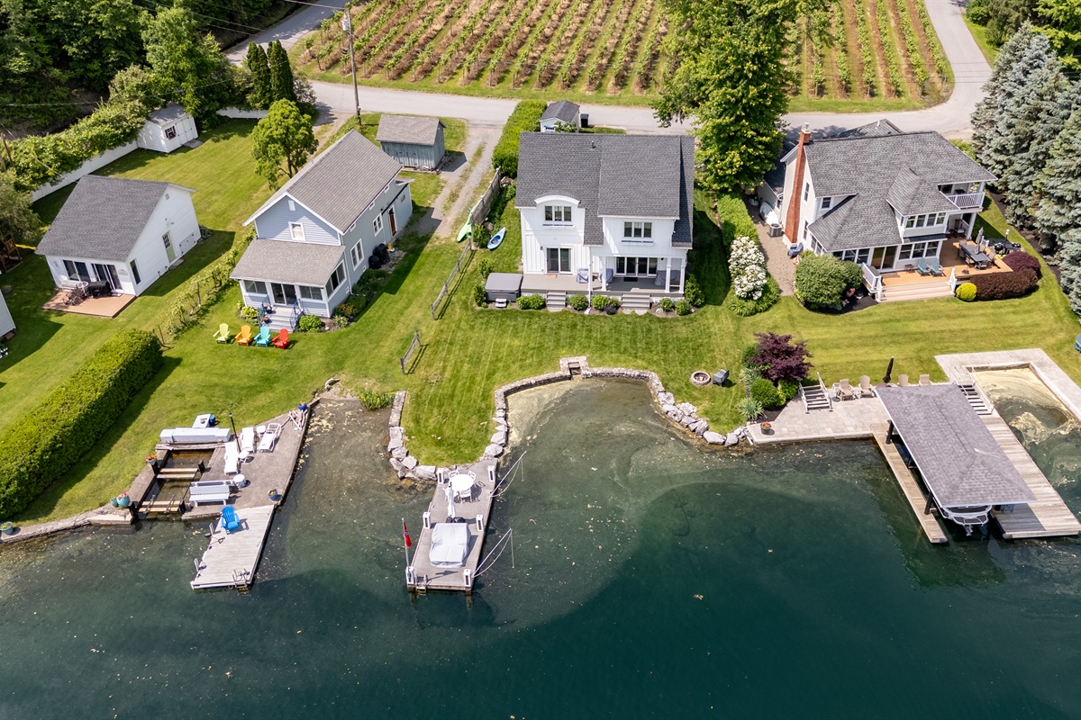 Stunning aerial view of a serene Finger Lakes waterfront retreat, complete with private dock, lush greenery, and charming lakefront homes—perfect for peaceful getaways and water adventures