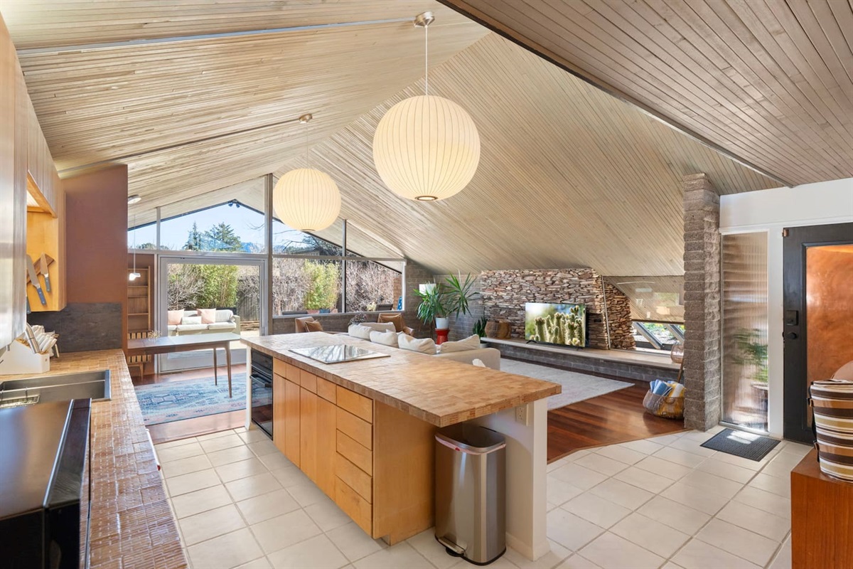 Stunning open-concept kitchen and living space with vaulted wood ceilings, oversized island, and seamless indoor-outdoor flow filled with natural light.