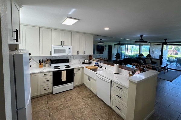 Fully stocked newly remodeled kitchen with farmhouse sink, bright countertops.