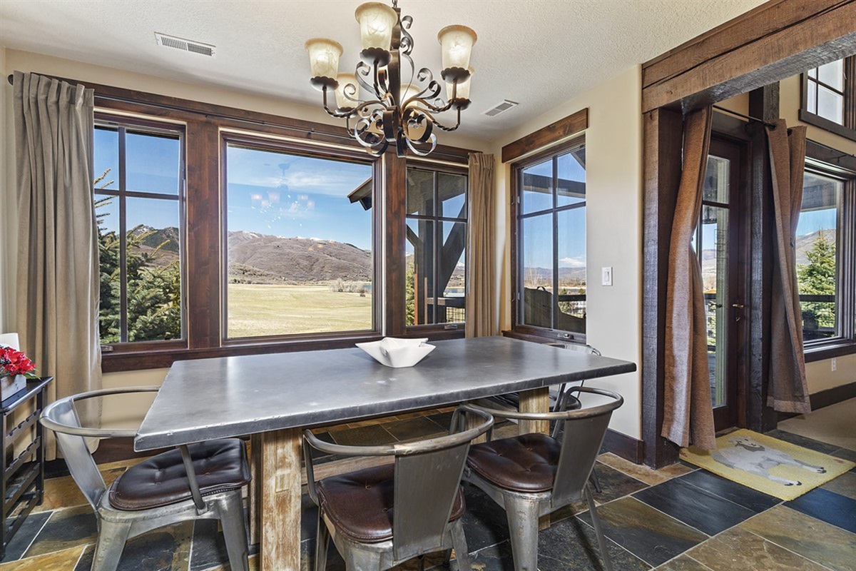 A dining area framed by expansive windows, offering stunning views of the mountains and an ideal setting for memorable meals in a bright, sophisticated space.