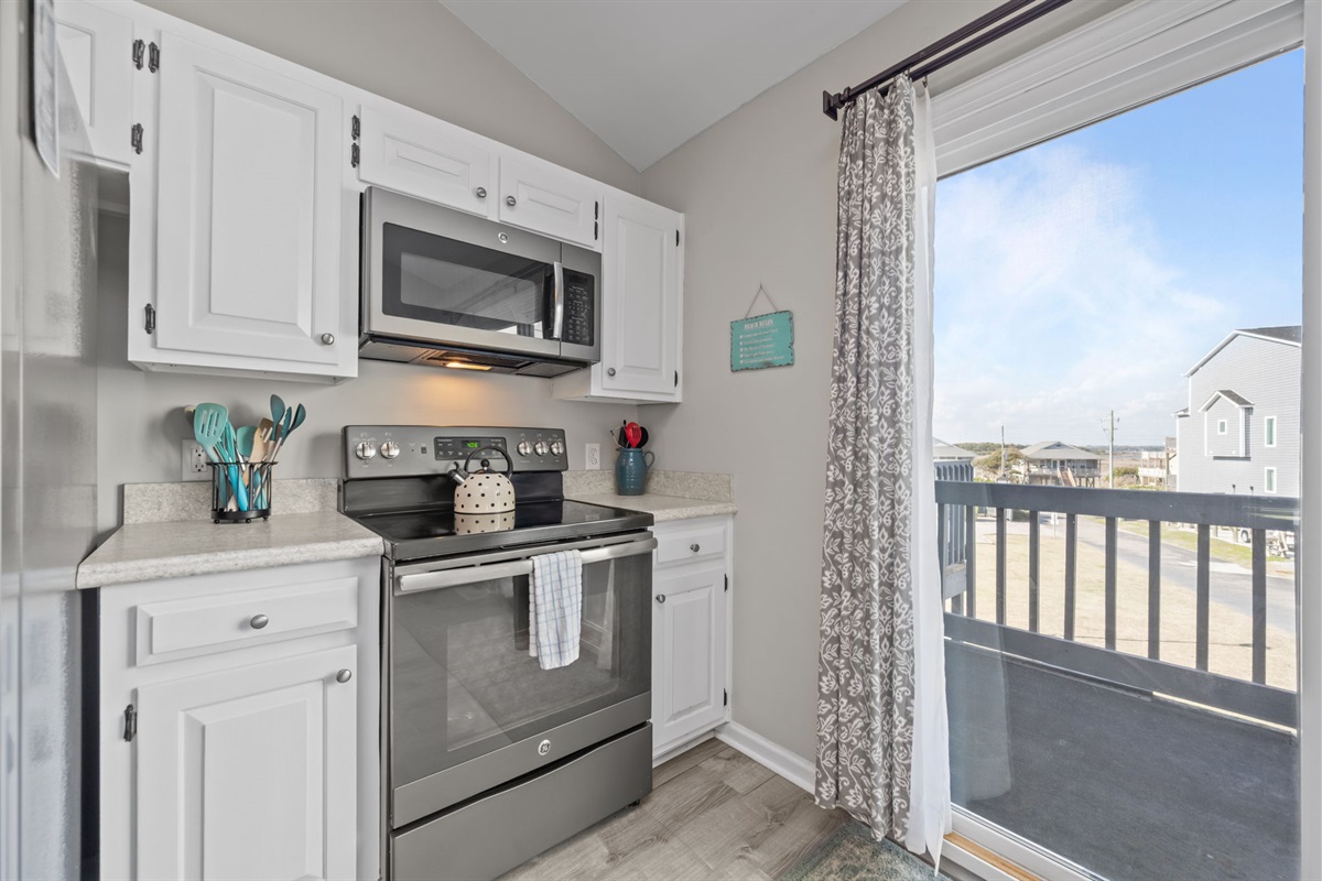 Bright and airy kitchen corner with stainless appliances, coastal touches, and a window that lets in plenty of natural light while you cook