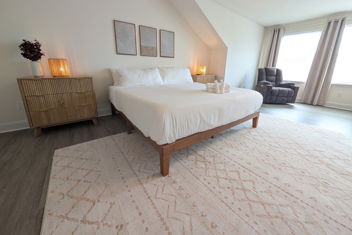 A bright and relaxing primary suite with generous floor space and a cozy sitting area.