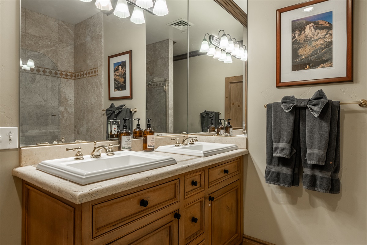 Spacious primary bath featuring dual sinks, ample storage, and warm wood cabinetry.