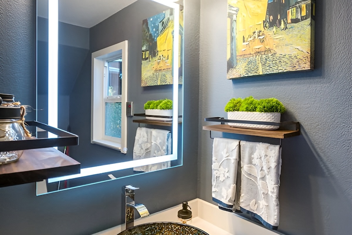 - Chic powder room with vessel sink and sleek illuminated vanity mirror  
- Dark accent wall and framed art create a sophisticated modern style  
- Floating shelves add both function and decorative touches to the space  
