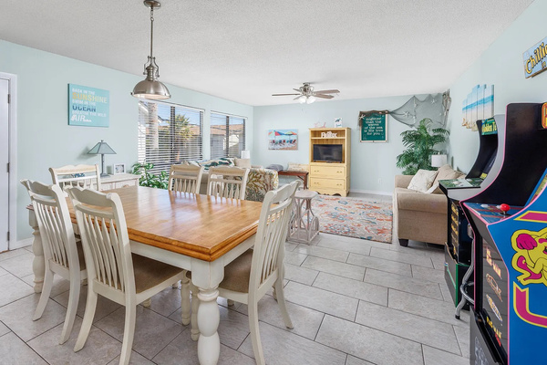Open-concept living & dining, arcade included. Gather the whole crew around the dining table (seats 6). Natural light pours in through the windows, and yes, those are arcade cabinets in the corner.