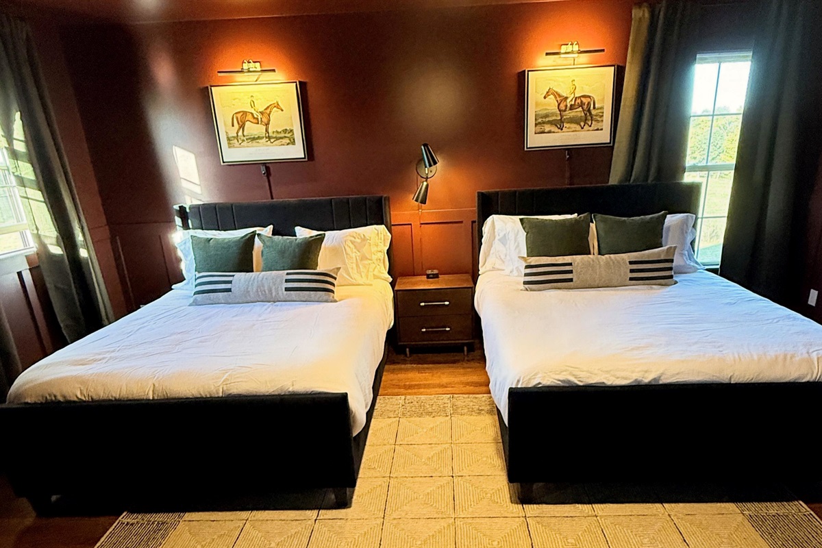 Bathed in rich auburn tones and soft, flattering light, this bedroom invites slow mornings and easy conversation — two queen beds set in refined textures and equestrian detail, offering a warm, subtly seductive sense of comfort and connection.