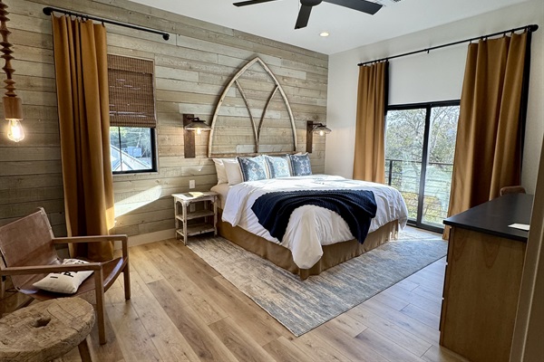 Inside Cutter's Quarters Bedroom #1 &mdash; a pillow-top king, a leather reading chair, and natural light upstairs at Gaines Ranch on the Square.