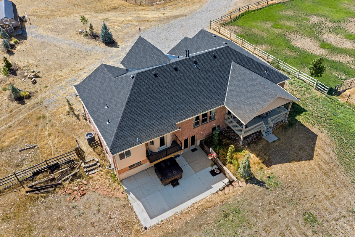 This elevated view highlights the home’s expansive footprint, covered deck, private hot tub area, generous outdoor space, and peaceful setting.