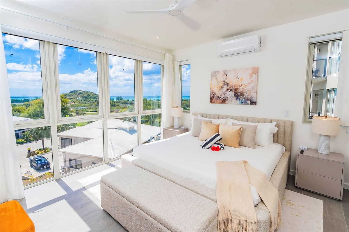 Master bedroom with king size bed, en-suite bathroom, air conditioning, ceiling fan, wall mounted tv, closet and gorgeous views of the ocean and hillside.