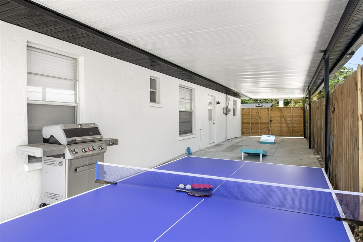 Covered outdoor area with ping pong, corn hole and grill. 