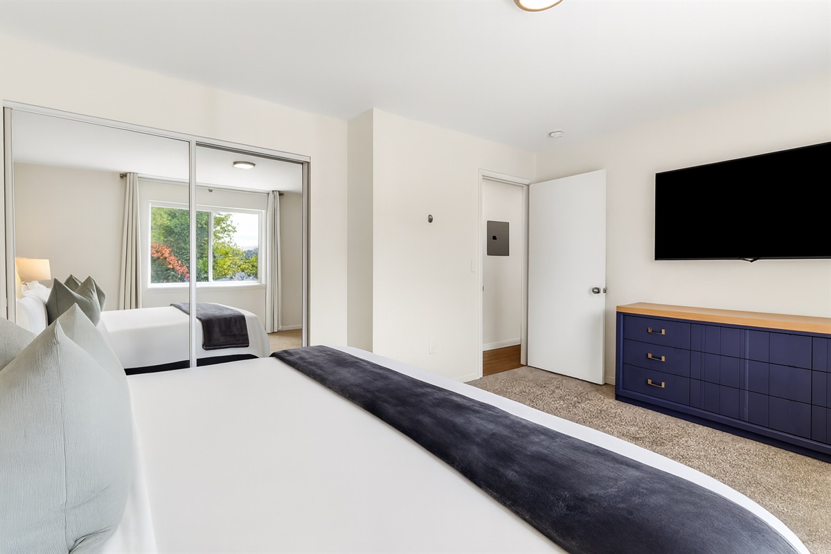 Full bedroom view with relaxing décor, blackout curtains, and private entertainment setup.