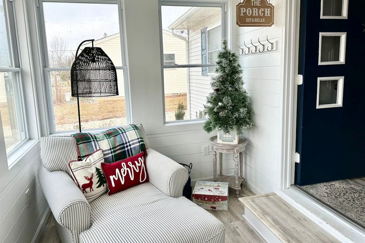 The holiday spirit extends into every corner of the home. In November, a bright sunroom is decked out for the season with a "Merry" pillow, a miniature flocked Christmas tree, and a comfortable striped chaise lounge—perfect for curling up with a blanket.