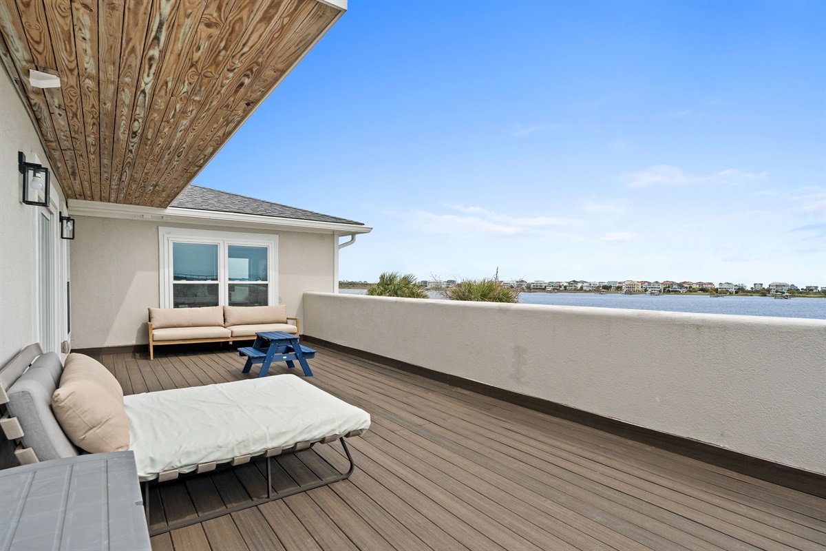 Expansive waterfront balcony with lounge seating and panoramic views