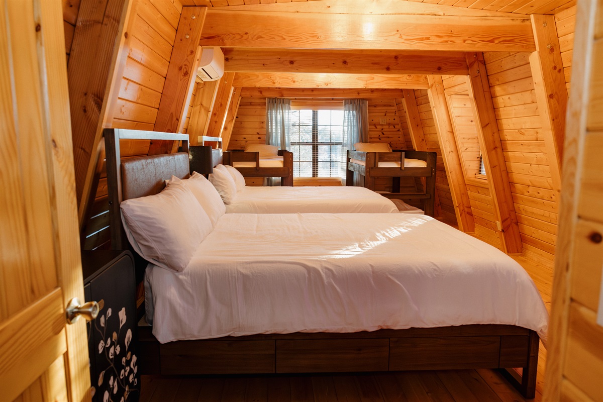 The Big Bedroom at Poppywood Pines features two queen beds plus twin bunk beds, perfect for families. This spacious Show Low loft offers flexible sleeping arrangements surrounded by dramatic A-frame beams, ideal after White Mountains hiking and fishing.