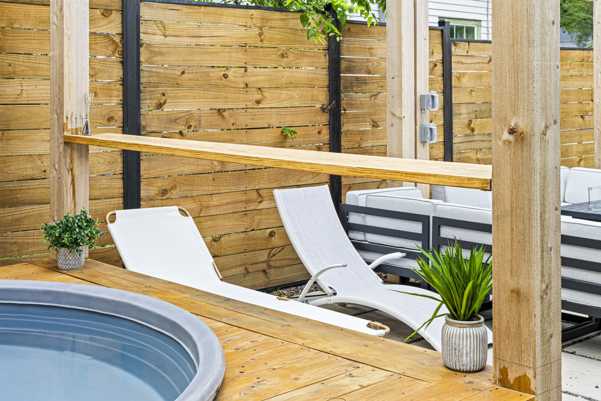 Relax in the sun by the hot tub with stylish lounge chairs and ample greenery!