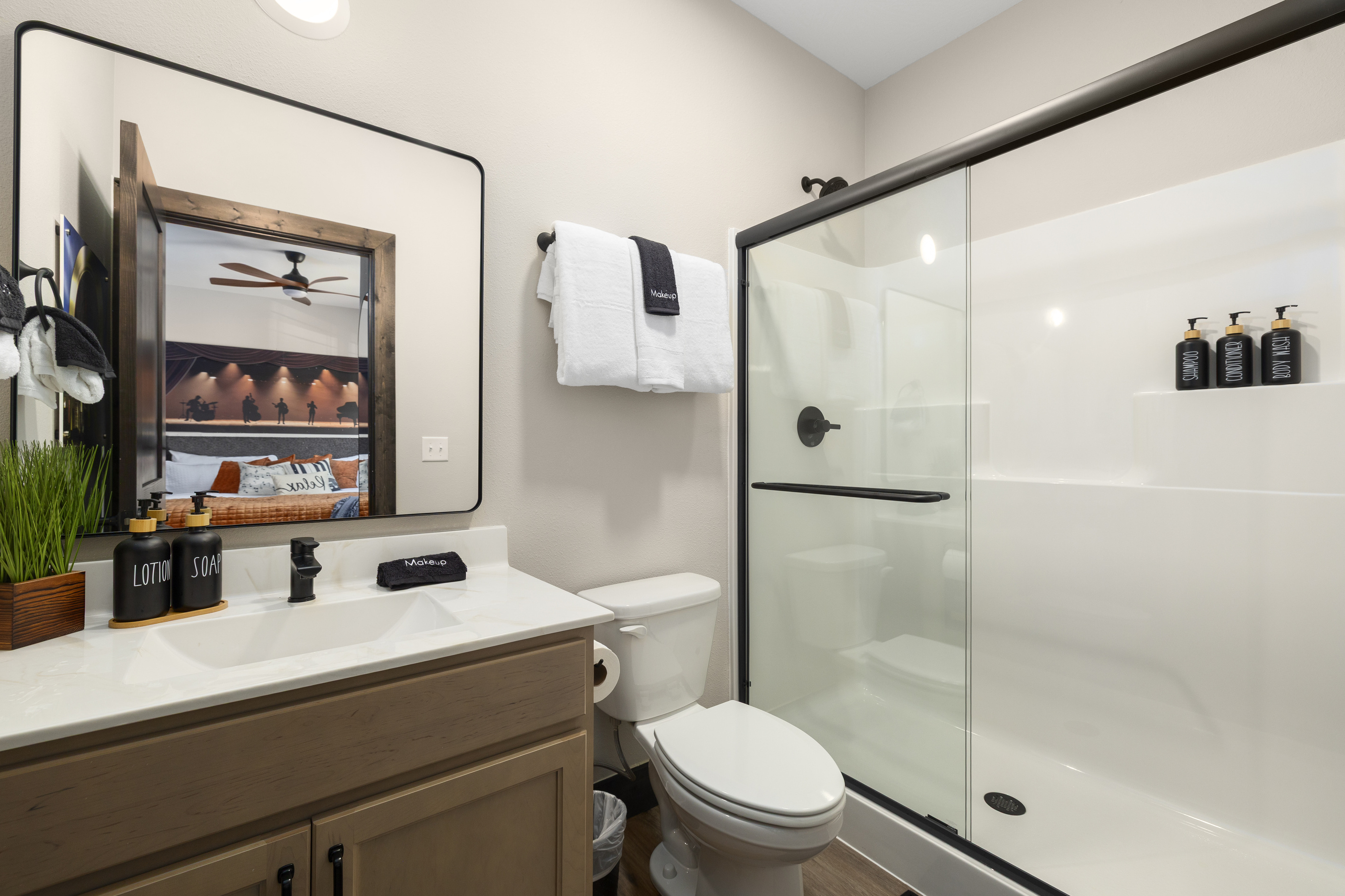 Walk-in shower, wood vanity, and a lit mirror in the ensuite.