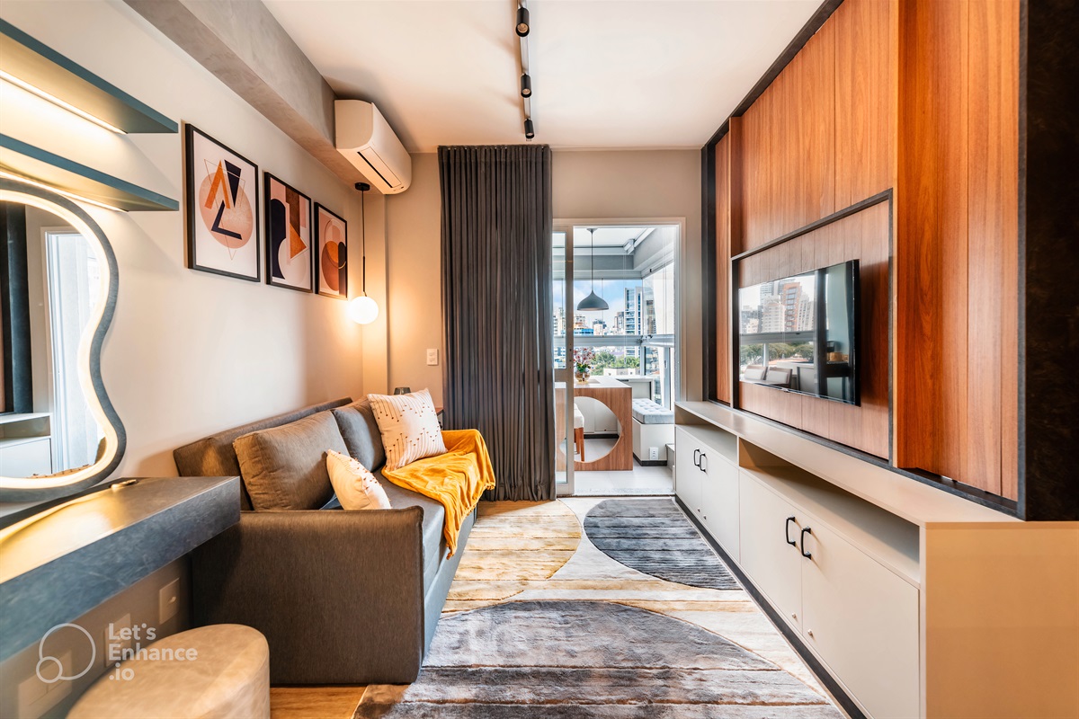 Sala moderna com ar-condicionado, TV Smart giratória, sofá-cama e iluminação aconchegante — ideal para relaxar ou trabalhar com vista para a varanda.