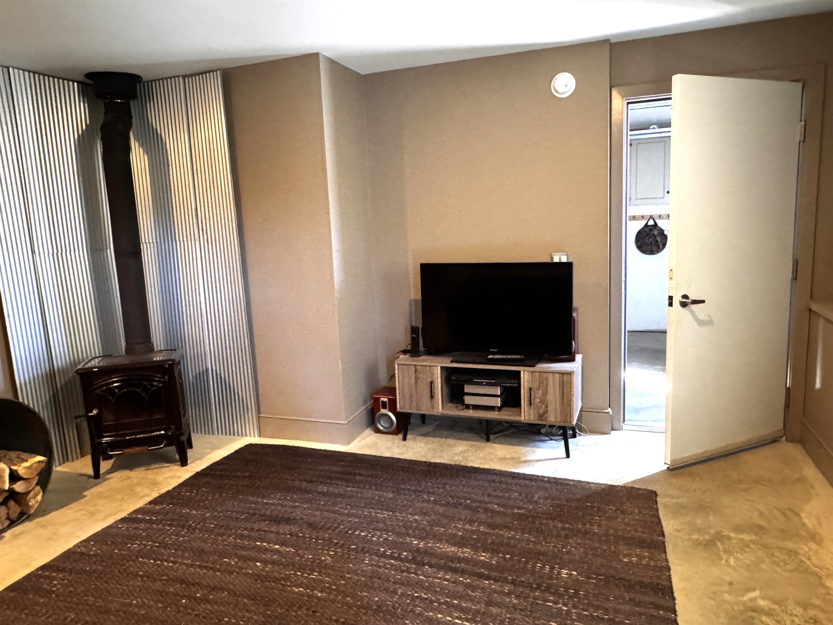 The home’s primary media room located on the lower level, featuring a smart Roku TV and cozy lounge area. This dedicated social space offers a quiet retreat for movie nights, positioned conveniently between the guest bedroom and the private garage.