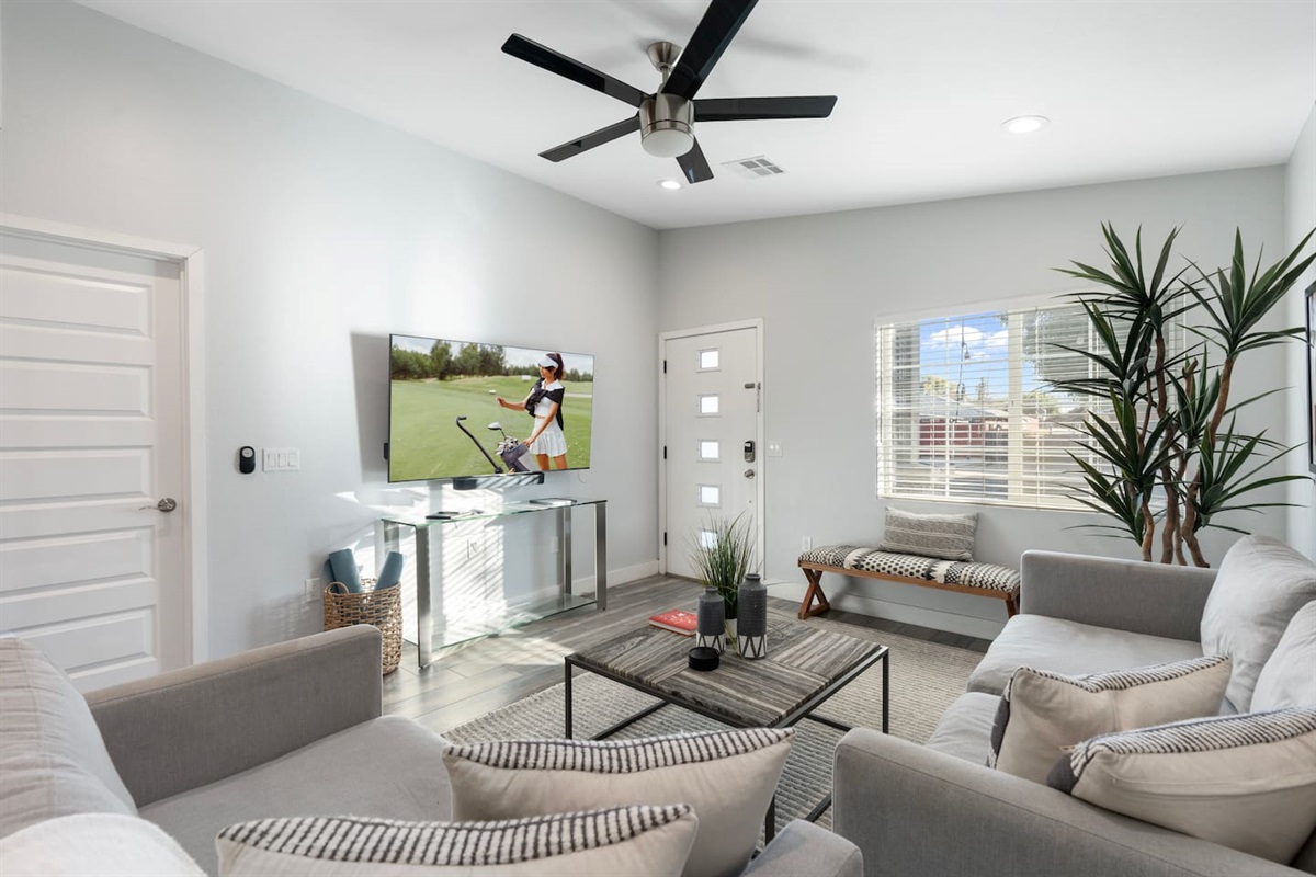 Bright and airy living room with large windows, cozy seating, and a sleek TV setup for your entertainment.