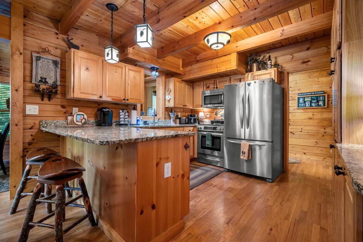 Rustic full kitchen equipped with granite countertops, stainless steel appliances, and warm wood finishes, complete with an eating bar and everything needed for cozy meals and morning coffee.