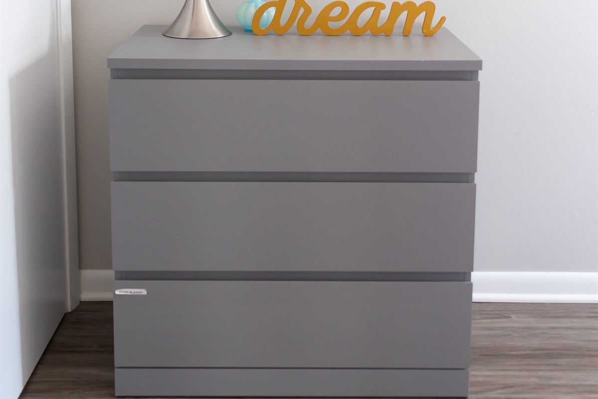 Dresser with extra blankets in bottom drawer.