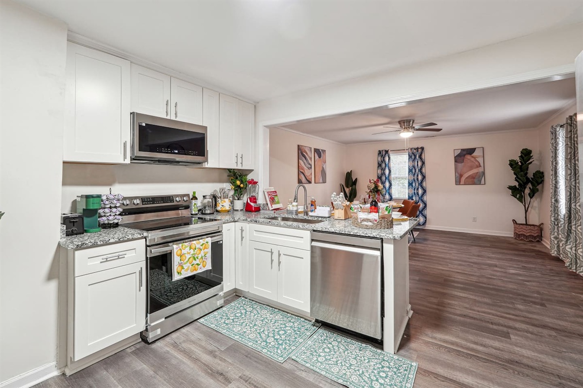 A fully equipped kitchen with a refrigerator, microwave, stove, oven,fridge, dishwasher, coffee maker, kettle, toaster, and blender. Includes plates, bowls, utensils, pots, and pans, plus four bar chairs for casual dining or socializing.
