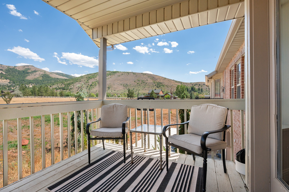 A private covered balcony offers comfortable seating and a peaceful place to enjoy morning coffee while overlooking the surrounding hills.