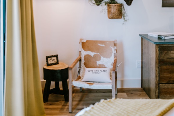 A welcoming sitting nook in the Lazy Spur Suite &mdash; a leather chair, handcrafted cowhide pillow, and curated Hill Country touches at Gaines Ranch on the Square.