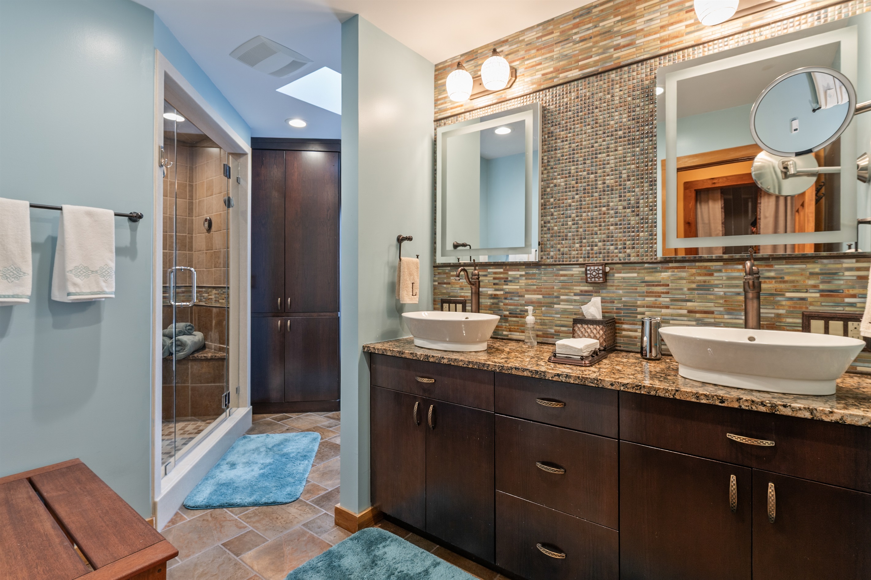 Luxurious double vanity bathroom with granite counters and warm lighting.