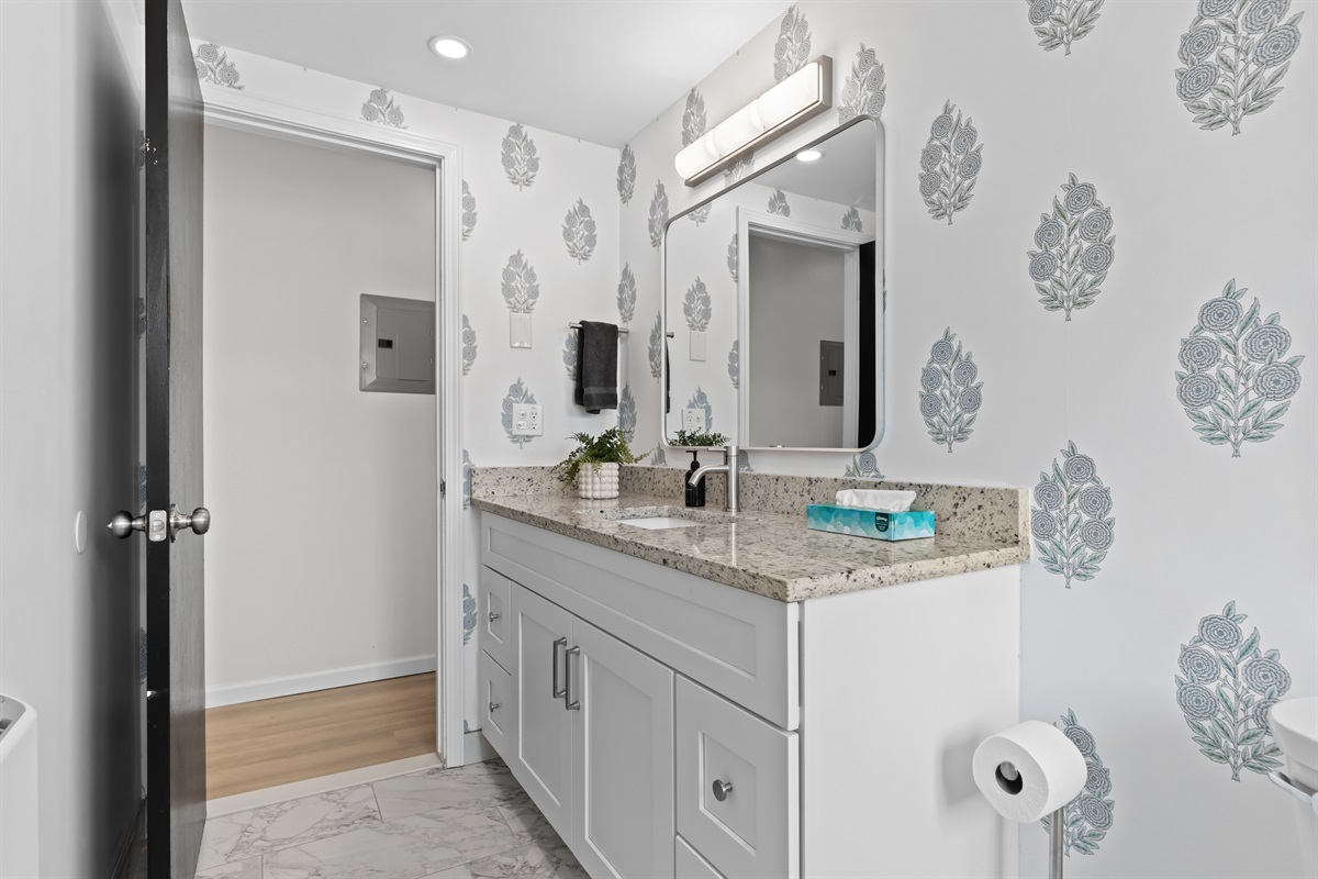 Chic patterned wallpaper adds a stylish touch to the bathroom space.