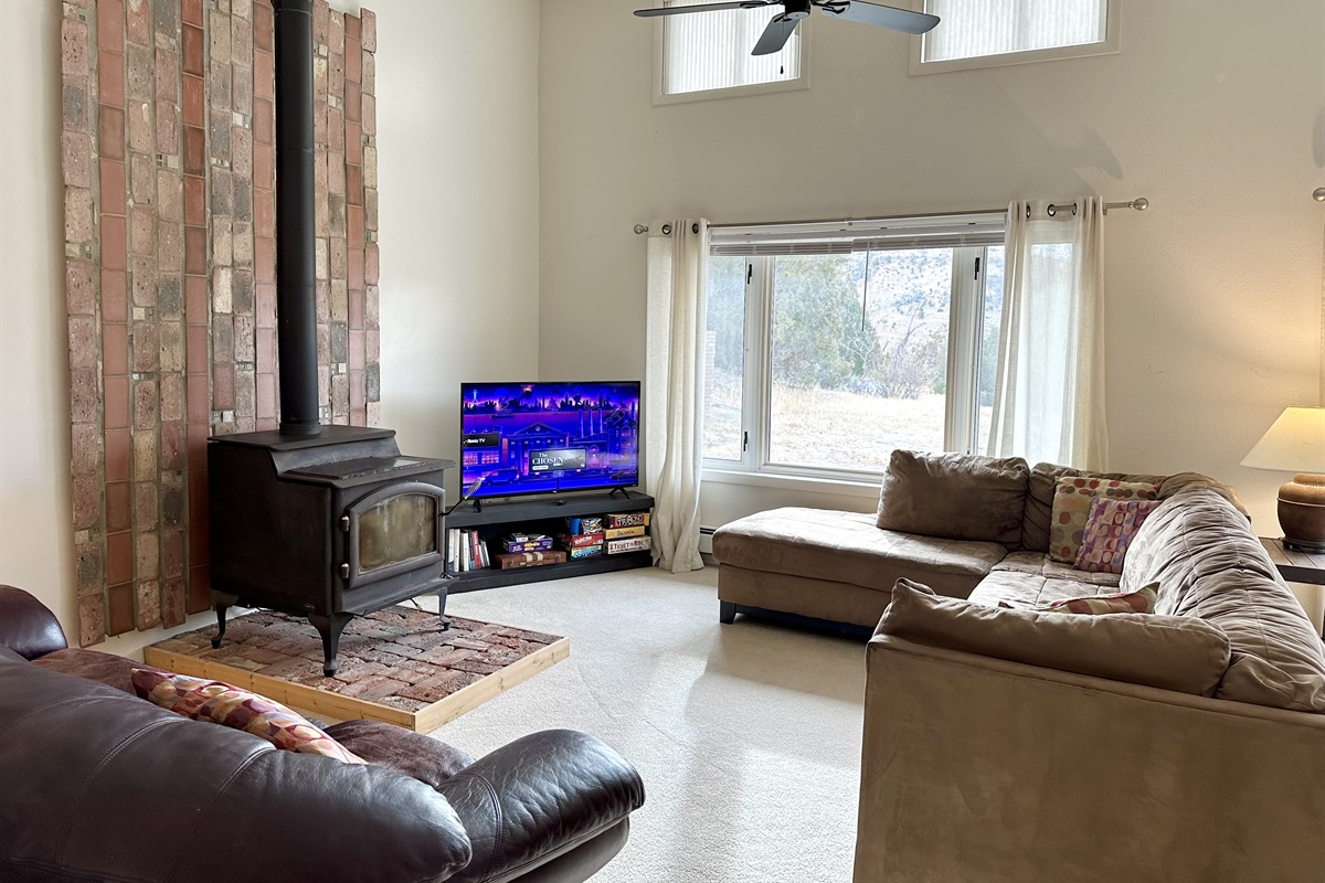 Large couches wrap around the wood stove and smart TV. Enjoy a collection of games and books.
